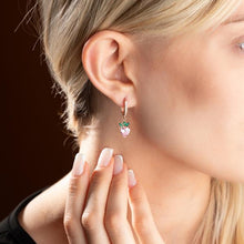 Close-up of a woman wearing a delicate earring with a green gemstone.