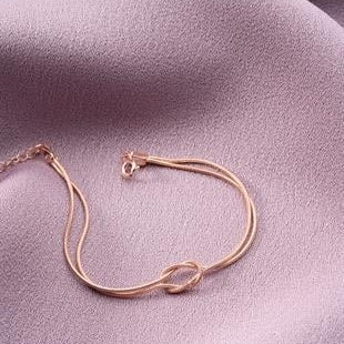 Rose gold bracelet on a soft pink fabric background