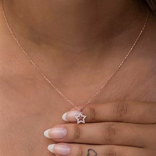Rose gold necklace with a star pendant worn by a person.