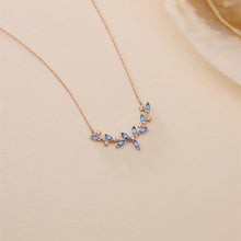 Rose gold necklace with blue gemstones on a beige background