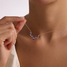 Necklace with blue stones being worn, highlighting the jewelry on a plain background.