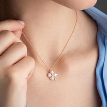 Close-up of a person wearing a rose gold necklace with a clover-shaped pendant.
