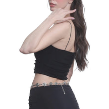 Woman wearing a black top and black pants with a silver chain belt on a white background