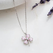 Silver necklace with a pink clover-shaped pendant on a light background