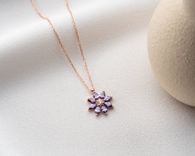 Close-up of a delicate sterling silver flower pendant with a birthstone accent.