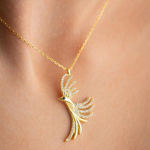 Gold necklace with a peacock feather pendant on a person's neck