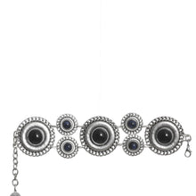 Silver bracelet with circular design and dark stones on a white background