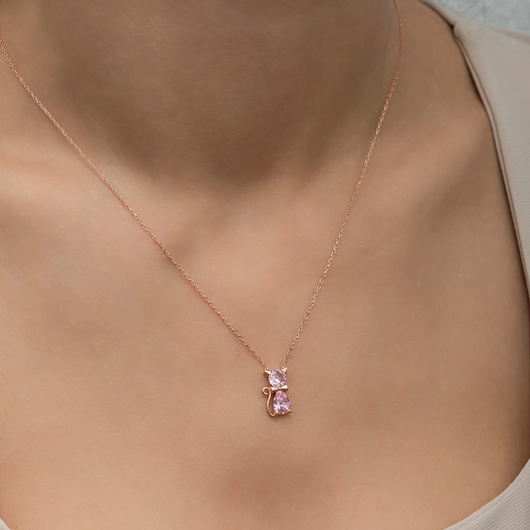 Rose gold necklace with a pink heart pendant on a mannequin