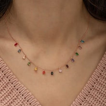 Necklace with colorful gemstones worn by a person against a neutral background
