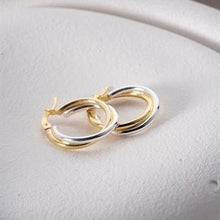 Pair of gold hoop earrings on a light gray background