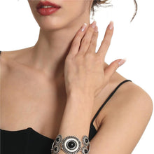 Woman wearing a black top and silver bracelet with a white background