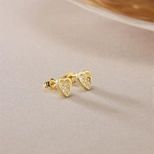 Gold heart-shaped earrings on a light beige background