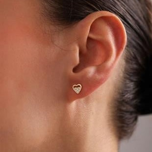 Heart-shaped earring worn by a person with a blurred background