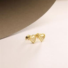Heart-shaped gold earrings on a light background