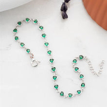 Silver bracelet with green heart-shaped stones on a white surface