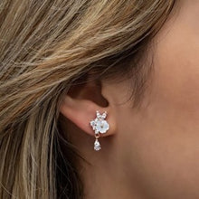 Close-up of an ear wearing a floral earring with a blurred background