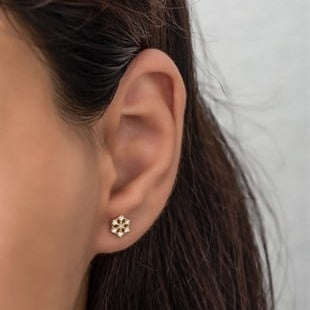 Close-up of an ear wearing a gold earring with a white background