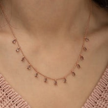 Rose gold necklace on a person wearing a pink crochet top