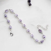 Silver necklace with purple gemstones on a light gray background