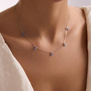 Necklace with small heart-shaped pendants on a person wearing a beige top.