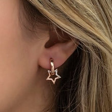Close-up of a person wearing a gold star-shaped earring.