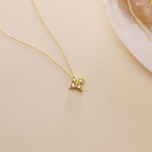 Gold necklace with a butterfly pendant on a beige background