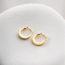Gold hoop earrings on a light gray surface
