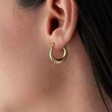 Close-up of a gold hoop earring worn by a person.