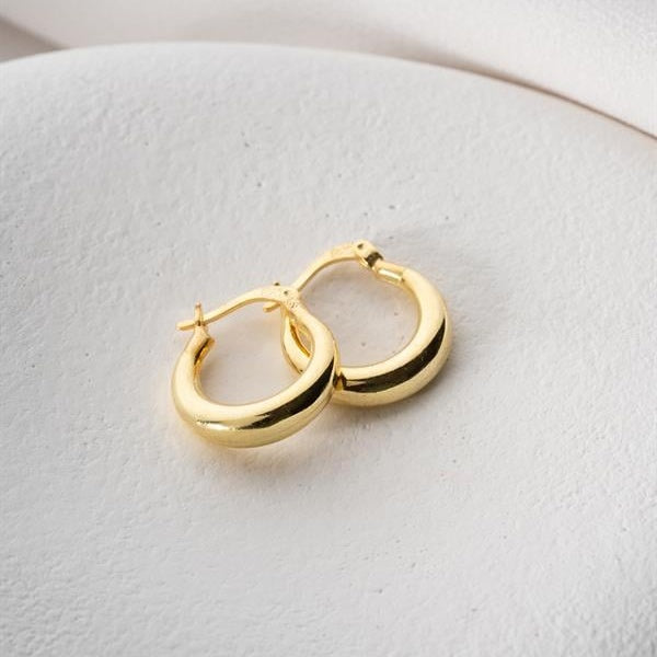 Gold hoop earrings on a light gray surface