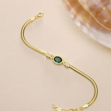 Gold bracelet with a green gemstone on a beige background