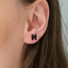 Close-up of an ear with a butterfly tattoo on a neutral background