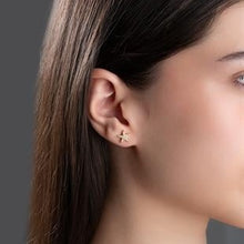 Close-up of a person wearing a gold earring with a dark background