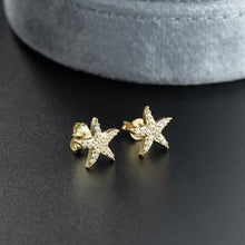 Gold starfish-shaped earrings on a dark surface