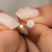 Close-up of a hand holding a diamond earring.