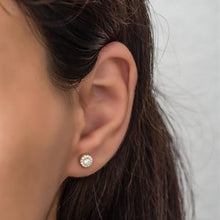 Close-up of an ear wearing a diamond earring with a plain background