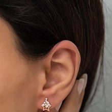Close-up of an ear wearing a star-shaped earring with a blurred background
