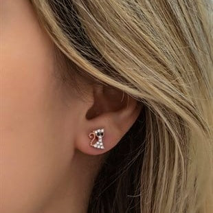 Close-up of a person wearing a bow-shaped earring with a neutral background