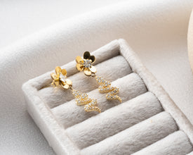 Moody lifestyle shot of gold serpent earrings with candles and books