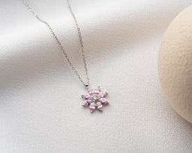 Elegant sterling silver flower necklace with pink gemstone detailing, perfect for nature lovers.