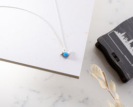 A celestial-themed opal bird charm necklace, a unique keepsake for nature lovers.