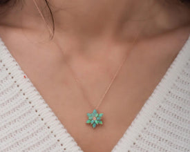 Nature-inspired spiritual jewelry featuring a lotus pendant with a glowing fire opal gemstone.