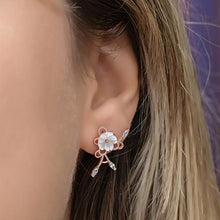 Close-up of an ear wearing a floral earring with a blurred background