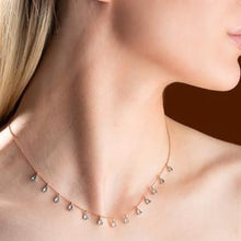 Necklace with small droplet pendants on a person's neck