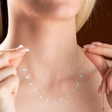 Necklace with small diamonds being held by hands against a dark background