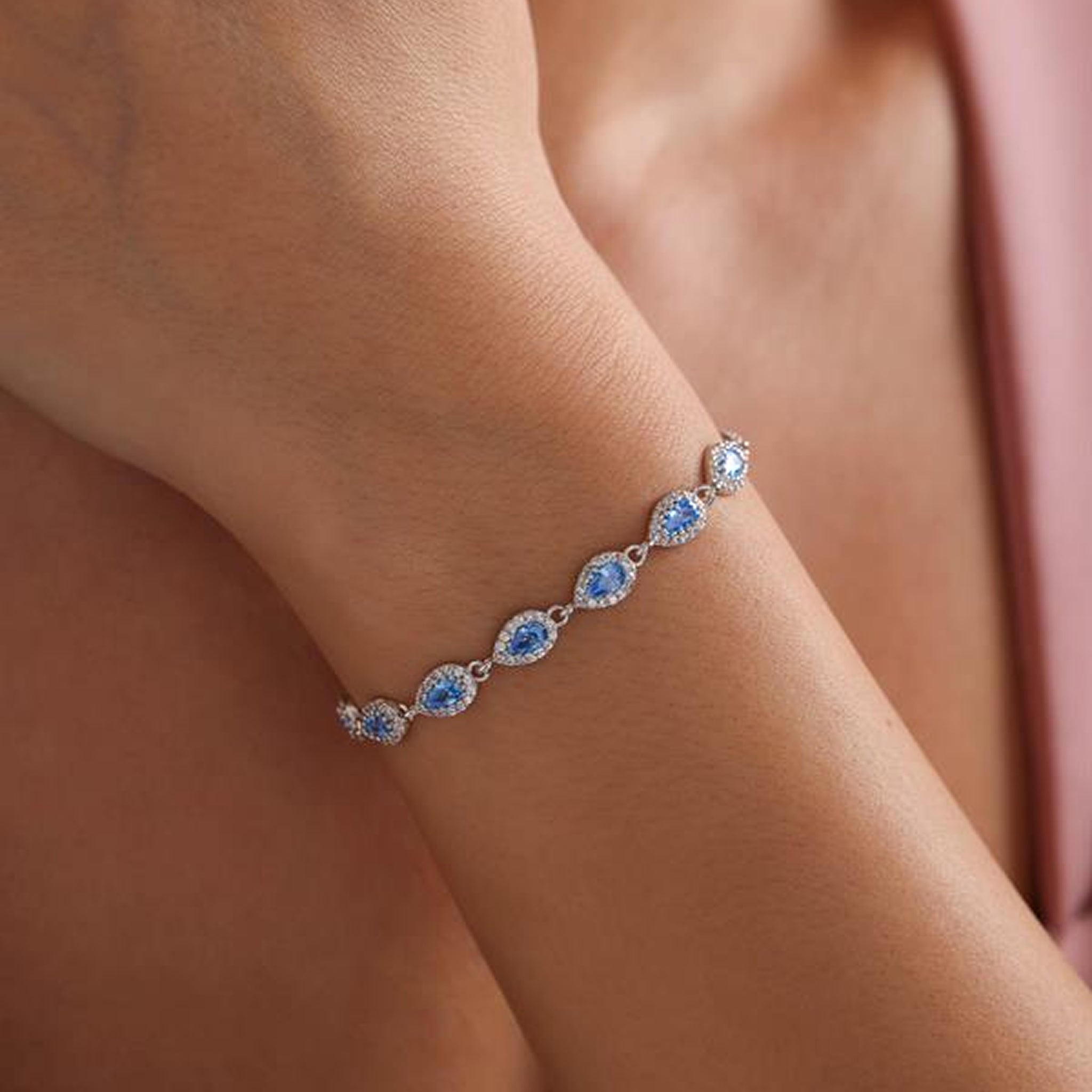 Silver bracelet with blue gemstones on a wrist against a blurred background