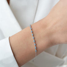Silver bracelet with blue stones on a wrist against a white background