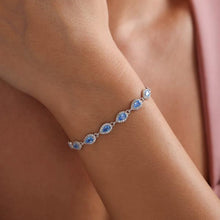 Silver bracelet with blue gemstones on a wrist against a blurred background