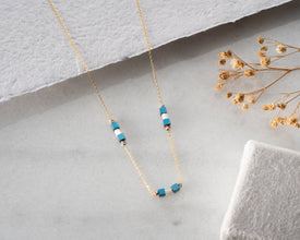 Close-up of silver bar necklace showing cube beads
