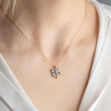 Rose gold necklace with a floral pendant on a person wearing a white top.