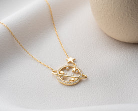 An astrology-themed jewelry set featuring the Saturn necklace, matching moon earrings, and a zodiac ring for a cosmic look.